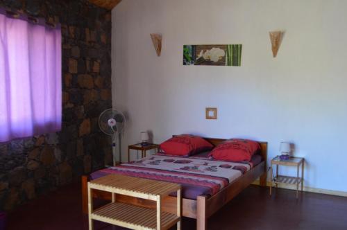 Schlafzimmer mit einem Bett mit roten Kissen und einem Fenster in der Unterkunft Casa De France in Porto Novo