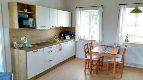 een keuken met witte kasten en een tafel met stoelen bij Ferienwohnungen Mühlenhof Oberseifersdorf in Mittelherwigsdorf