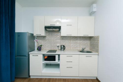 Cozy Apartment on Gmyri 12b near metro Poznyaki في كييف: مطبخ أبيض مع حوض وثلاجة