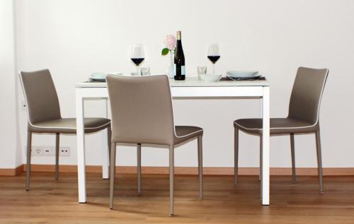 a white table with three chairs and a bottle of wine at Wohnen am Roseneck in Berlin