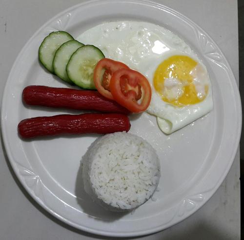 a plate of food with sausage rice and an egg at Carribean Transient House in Lucap