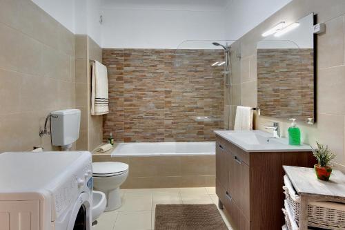 een badkamer met een bad, een toilet en een wastafel bij Apartamentos do Atlantico in Albufeira