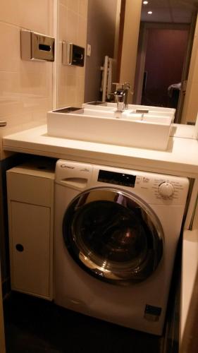 une machine à laver dans une salle de bain avec un lavabo dans l'établissement Aparthotel Paris 15 Porte de Versailles, à Issy-les-Moulineaux