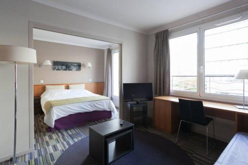 Cette chambre comprend un lit, un bureau et une fenêtre. dans l'établissement Aparthotel Paris 15 Porte de Versailles, à Issy-les-Moulineaux
