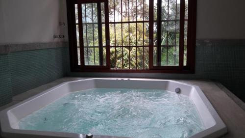 a bath tub filled with water in front of a window at Quarto particular (24m²) - 03 pessoas in Pedra Azul