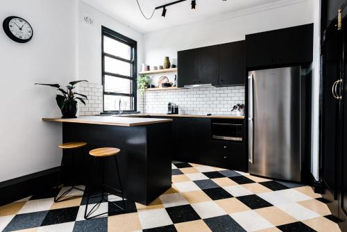 uma cozinha com armários pretos e um frigorífico de aço inoxidável em Sydney Park Hotel em Sydney