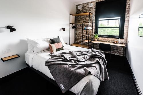 a bedroom with a bed and a brick wall at Sydney Park Hotel in Sydney