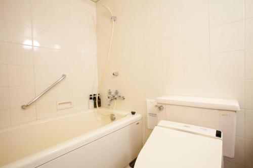 a white bathroom with a toilet and a bath tub at Ranzan in Kyoto