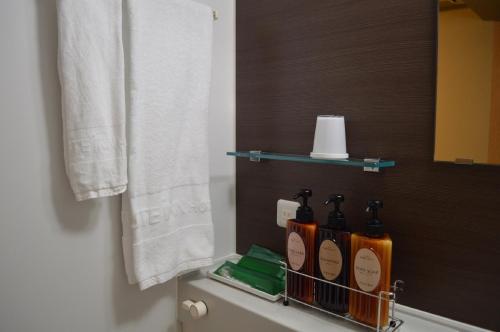 - une salle de bains avec des bouteilles à l'arrière des toilettes dans l'établissement HOTEL ROUTE-INN Osaka Takaishi Hagoromo Ekimae, à Takaishi