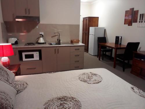 a bedroom with a bed and a kitchen with a sink at Moe Motor Inn - Contactless 24 hour Checkinn Available in Moe