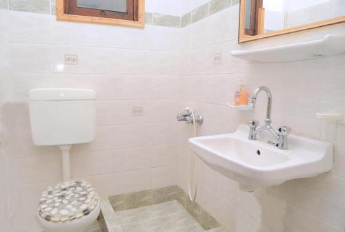 a white bathroom with a sink and a toilet at The Delfini Hotel in Agia Marina Aegina