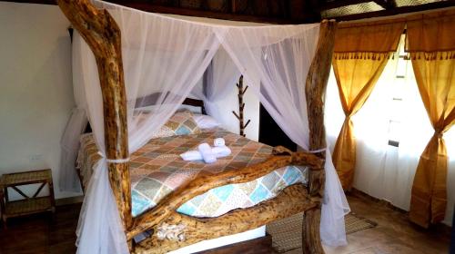 a bedroom with a canopy bed with white towels on it at Quetzal Dorado Eco-Lodge by Mareygua in El Zaino