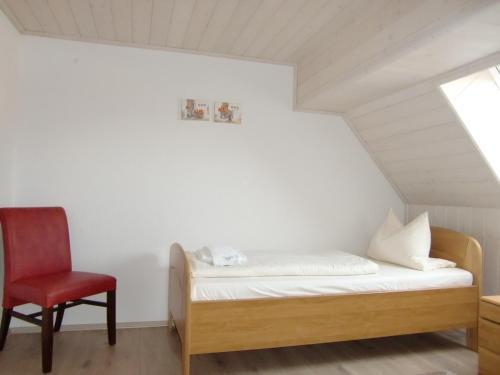 a bedroom with a bed and a red chair at Landhotel Fuchsbau in Vohenstrauß