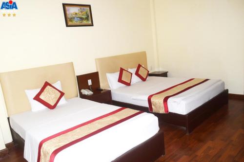 two beds in a hotel room with white walls at Asia Hotel Can Tho in Can Tho