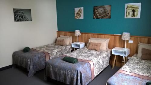 a room with three beds and two ottomans at Moe Motor Inn - Contactless 24 hour Checkinn Available in Moe