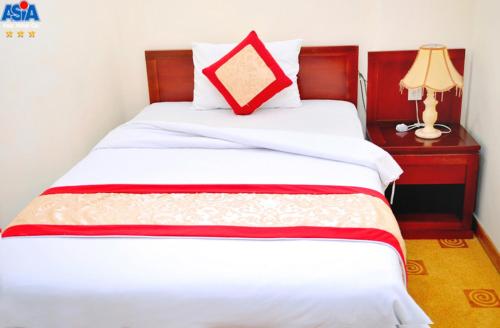 a bed with a red pillow on top of it at Asia Hotel Can Tho in Can Tho