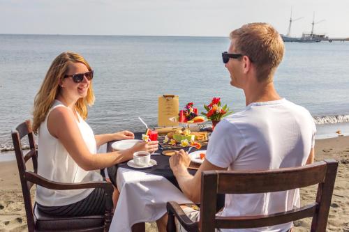 Un uomo e una donna seduti a un tavolo sulla spiaggia di Adi Assri Beach Resorts And Spa Pemuteran a Pemuteran