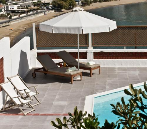 an umbrella and lounge chairs next to a swimming pool at Mare Vista Hotel - Epaminondas in Batsi