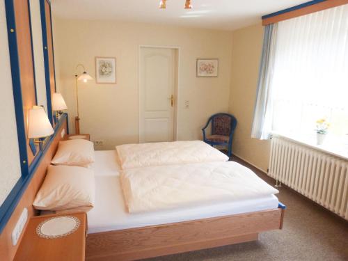 Un dormitorio con una cama blanca y una ventana. en Bungalow *Ual Welhüs*, en Norddorf