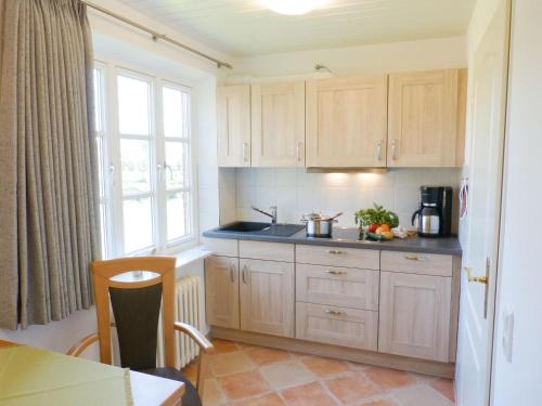 Una cocina con gabinetes de madera y encimera. en Bungalow *Ual Welhüs*, en Norddorf