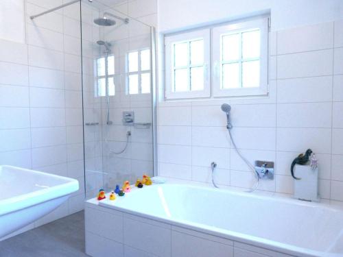 y baño blanco con bañera y ducha. en Ferienhaus *Koggenhüs* en Norddorf