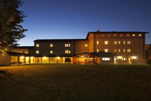 a large building at night with its lights on at Hotel Naonis in Cordenons