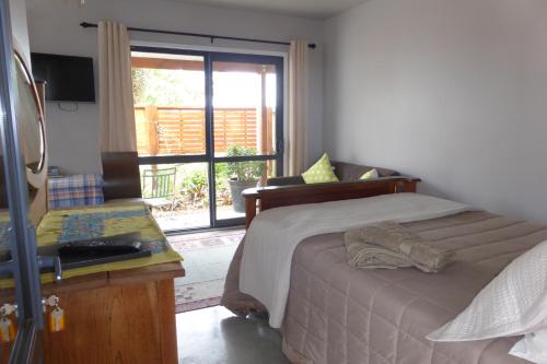 a bedroom with a bed and a sliding glass door at Bungalow on Bell Common in Tauranga