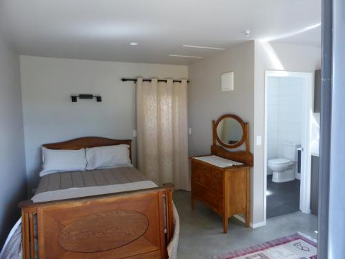 a bedroom with a bed and a mirror and a sink at Bungalow on Bell Common in Tauranga