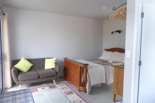 a small bedroom with a bed and a couch at Bungalow on Bell Common in Tauranga