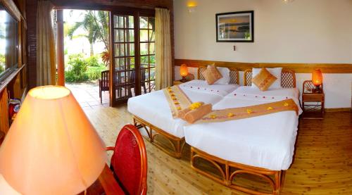 Little Muine Cottages Resort في موي ني: غرفة نوم فيها سريرين ومصباح