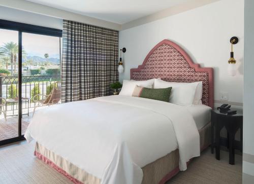 um quarto com uma grande cama branca e uma varanda em Sands Hotel and Spa em Indian Wells