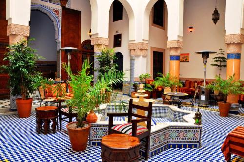 a lobby with tables and chairs and potted plants at Riad Ahlam in Fès