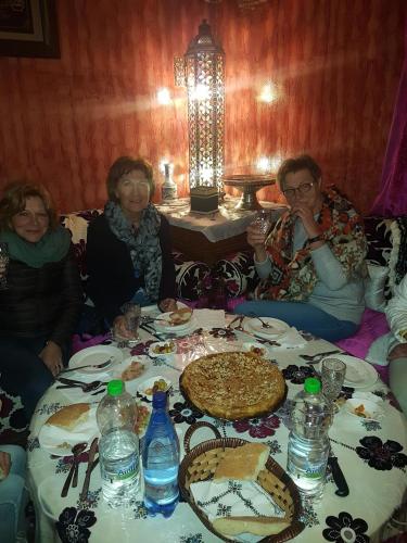 a group of people sitting around a table with a pizza at Kasabah Senhaji in Moulay Idriss Zerhoun