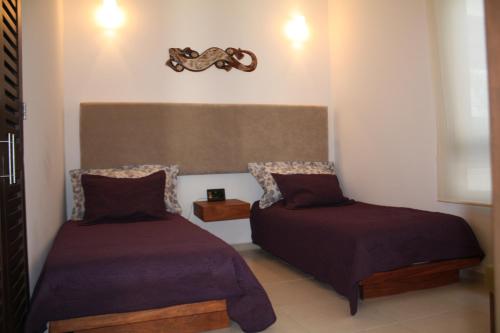 a room with two beds and a clock on the wall at TAO Modern Retreat in Akumal