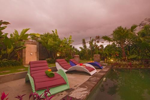 a group of chairs sitting next to a pool at Ratna Villa 4 in Ubud