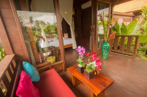 a living room with a red couch and a table with flowers at Ratna Villa 4 in Ubud