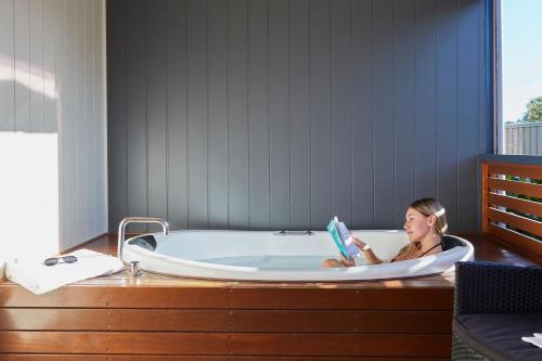 Eine Frau, die in einer Badewanne sitzt und ein Buch liest. in der Unterkunft BIG4 Breeze Holiday Parks - Busselton in Busselton