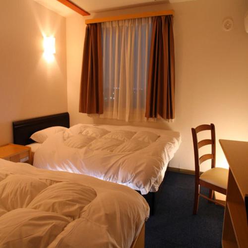 草加市にあるホテル朋泉 草加のベッド2台と窓が備わるホテルルームです。