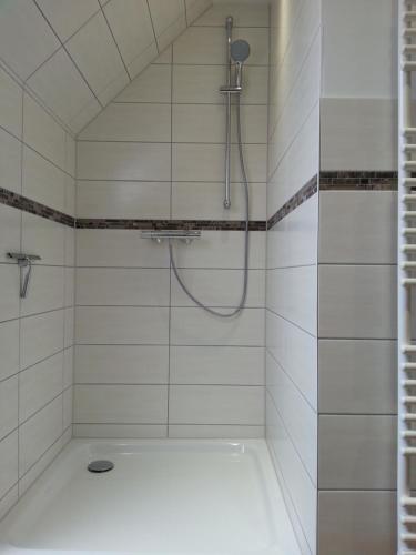 a white tiled shower with a shower head at Ostseebrise-Fehmarn in Fehmarn