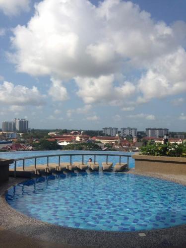 a large swimming pool with chairs and a bridge at Julia's Cottage in Kota Bharu