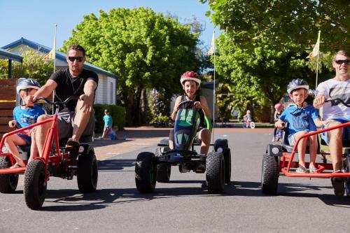 a man and three children riding onicycles down the street at BIG4 Breeze Holiday Parks - Busselton in Busselton