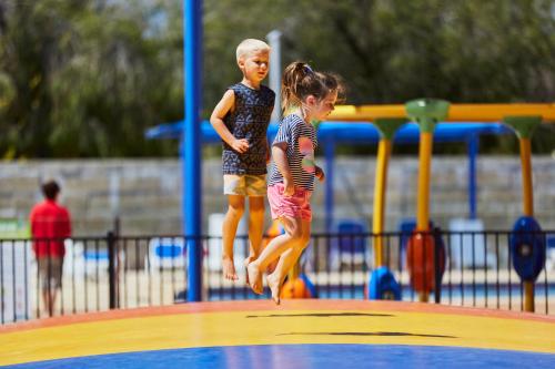two young children jumping on a playground at BIG4 Breeze Holiday Parks - Busselton in Busselton