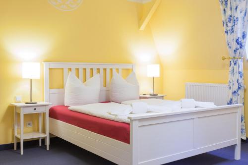 a bedroom with a white bed with white pillows at Parkhotel Muldental in Colditz