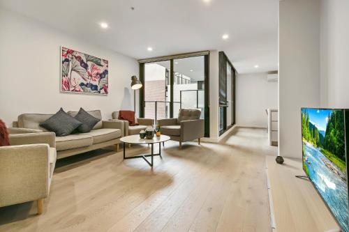 a living room with a couch and a tv at Melbourne City Apartments - Teri in Melbourne