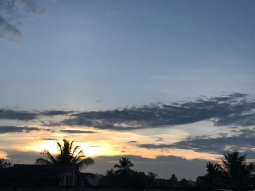 a sunset with palm trees and a cloudy sky at Resident View Homestay in Kandy