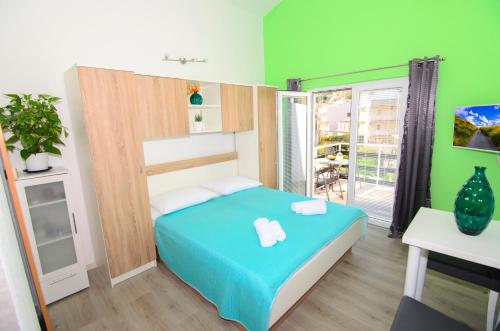 Un dormitorio con una cama azul y paredes verdes en Apartments Vodanović, en Podgora