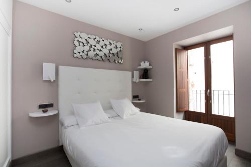 a white bedroom with a white bed and a window at La Sepia Boba (Adults only) in Peñíscola