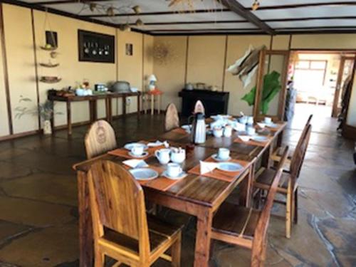 a large wooden table with chairs in a room at Halala Africa Lodge - Eagle Rock Lodge in Malabar
