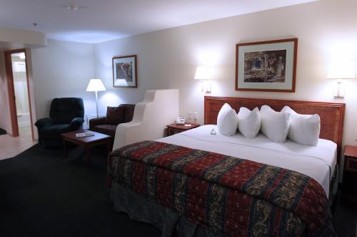 ein Hotelzimmer mit einem großen Bett und einem Stuhl in der Unterkunft Garden Place Suites in Sierra Vista