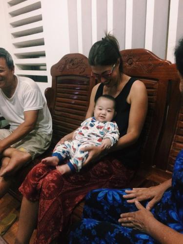 a woman holding a baby sitting on a couch at Vietnam Phuot Real Home in Kon Tum